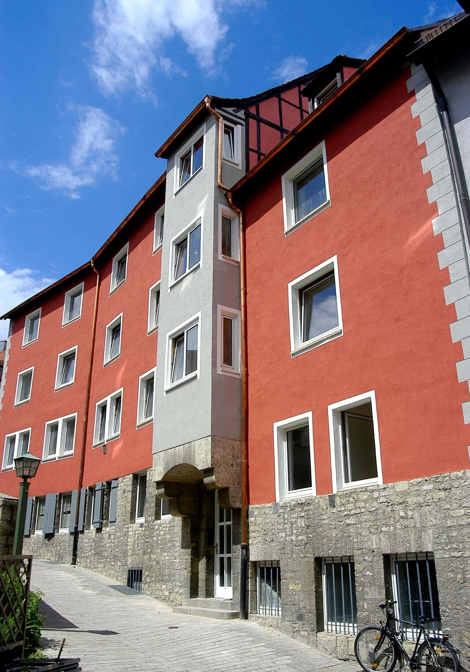 Dreigeschossiges Wohngebäude mit orangener Fassade und ausgebautem Dachgeschoss